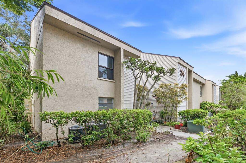 A two-story apartment building exterior with beige stucco, horizontal siding, and surrounding landscaping — 4873 PURITAN CIRCLE UNIT 2401, TAMPA, FL