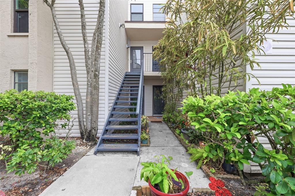 An exterior view of a multi-story building featuring an outdoor metal staircase leading to a balcony — 4873 PURITAN CIRCLE UNIT 2401, TAMPA, FL