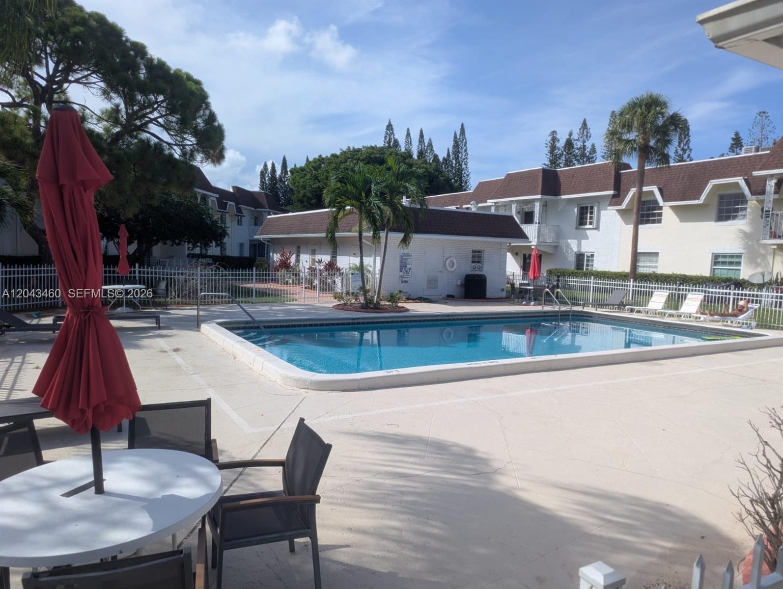 A rectangular swimming pool is surrounded by a concrete deck, patio furniture, and apartment buildings — 700 SE 2nd Ave # 313, Deerfield Beach FL 33441, DEERFIELD BEACH, FL