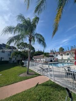A palm tree stands next to a fenced swimming pool outside a multi-story residential building — 700 SE 2nd Ave # 313, Deerfield Beach FL 33441, DEERFIELD BEACH, FL