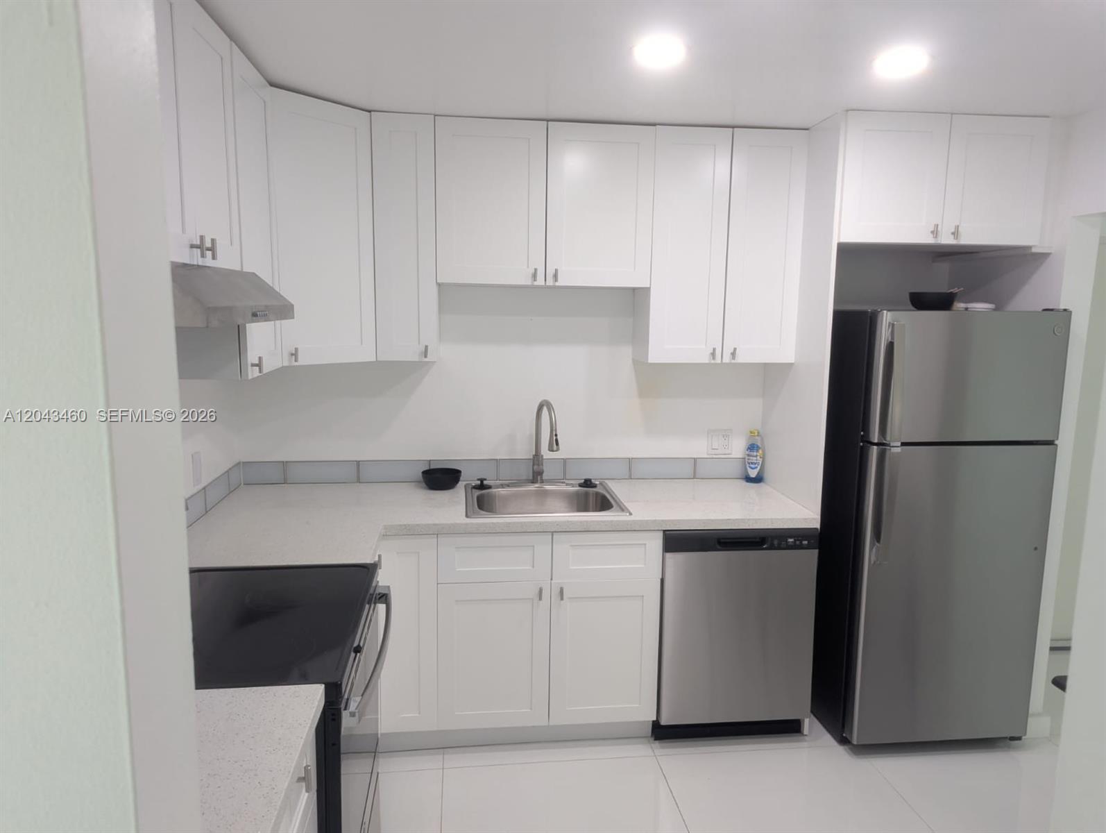 A kitchen features white cabinets, stainless steel appliances, and light-colored countertops — 700 SE 2nd Ave # 313, Deerfield Beach FL 33441, DEERFIELD BEACH, FL