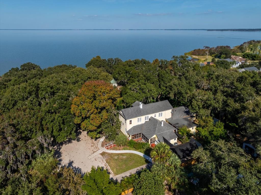 An aerial view shows a large house nestled in a wooded area beside a lake — 620 N TUBB STREET, OAKLAND, FL