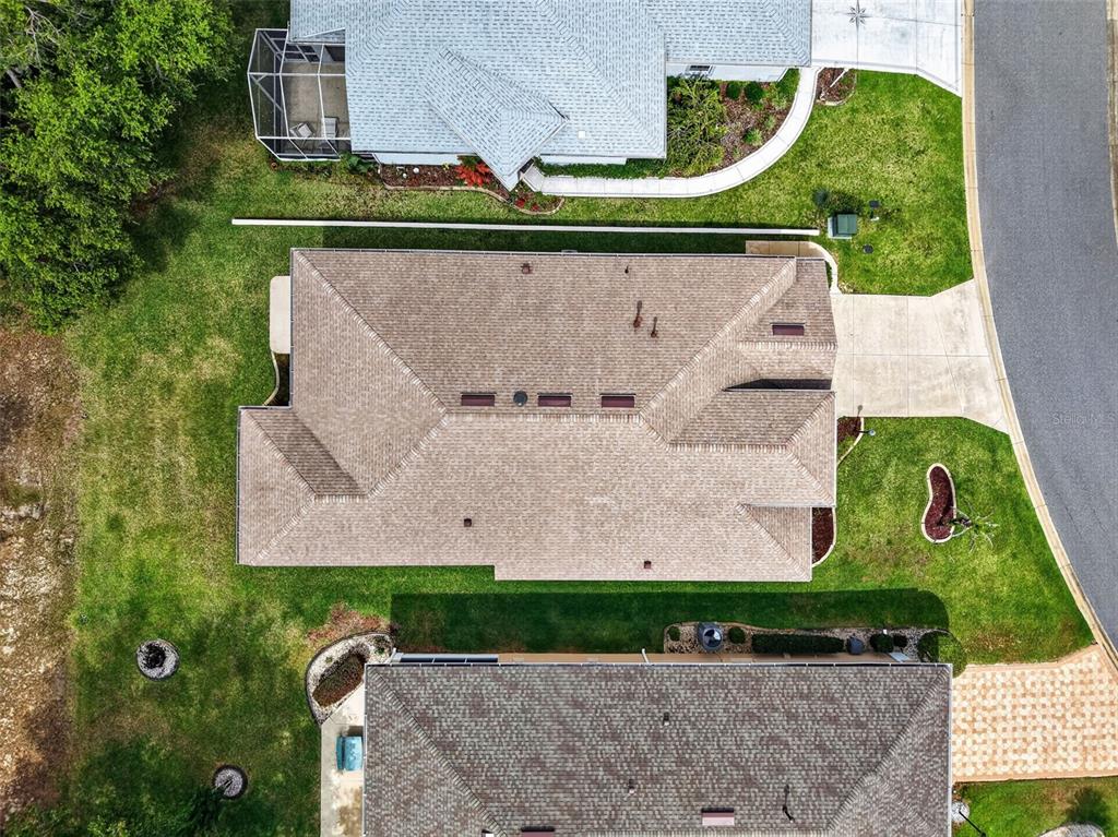 An aerial view shows the roof of a house surrounded by lawns and neighboring homes — 20634 QUEEN ALEXANDRA DRIVE, LEESBURG, FL