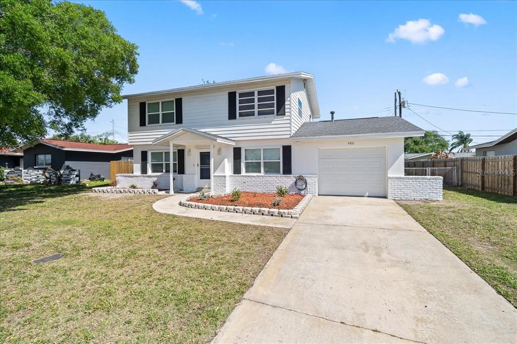 A two-story white house with a garage, a front lawn, and a paved driveway — 480 SABAL AVENUE, MERRITT ISLAND, FL
