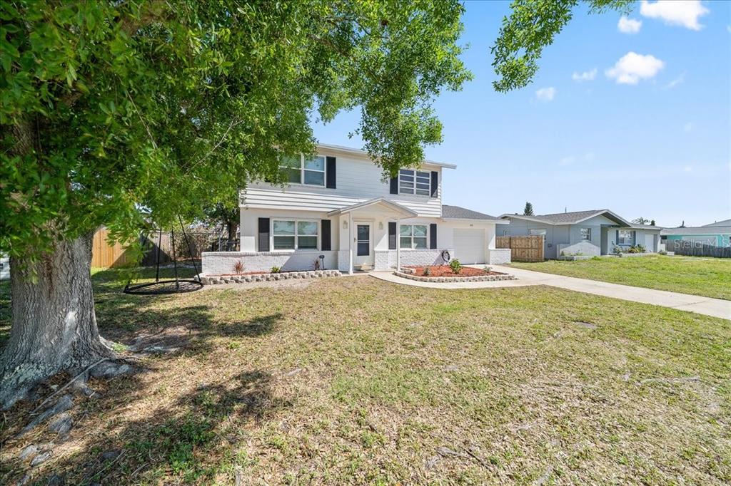 A two-story white house with black shutters sits on a grassy lot with a tree — 480 SABAL AVENUE, MERRITT ISLAND, FL