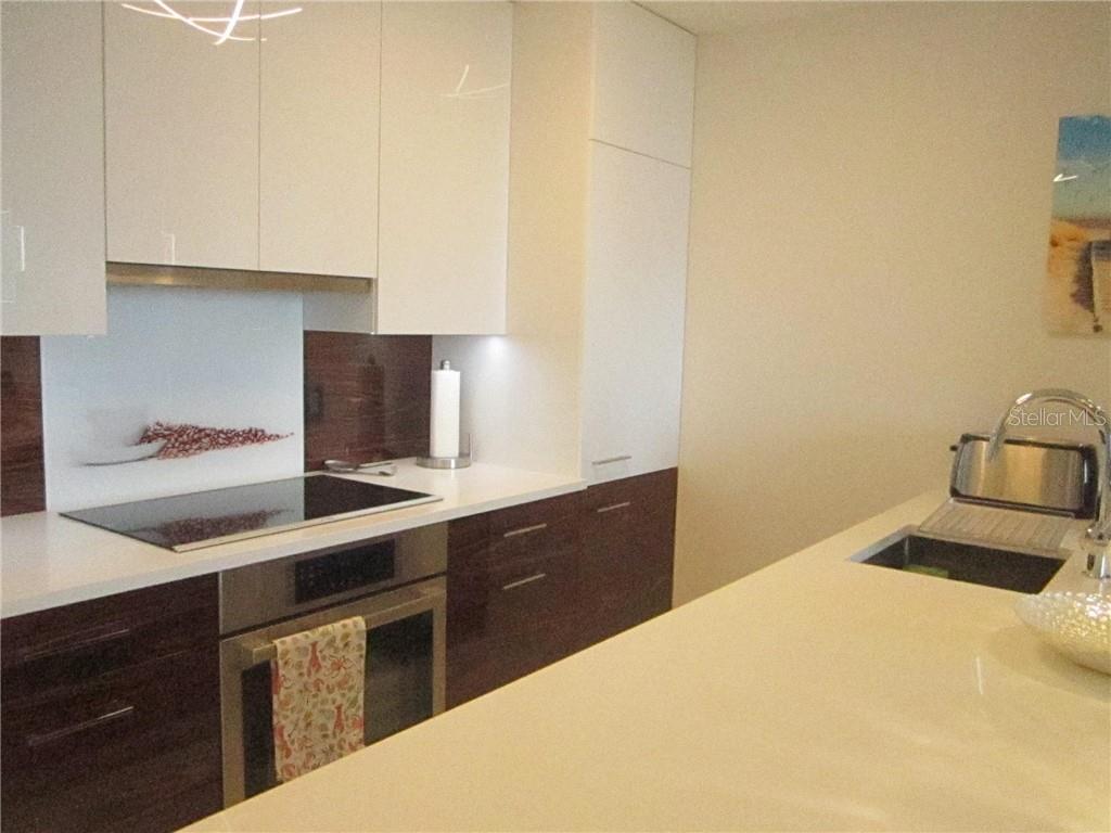 A modern kitchen features white upper cabinets, dark wood lower cabinets, and a white countertop — 750 N TAMIAMI TRAIL UNIT 705, SARASOTA, FL