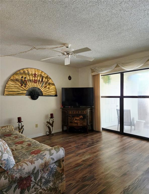 A dining room with a glass table, six chairs, wood-look flooring, and wall art — 6224 PRINCIPIA DRIVE UNIT 4, FORT MYERS, FL