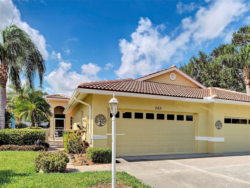 A tan, single-story house with a two-car garage and a tile roof — 249 VISTA DEL LAGO WAY, VENICE, FL