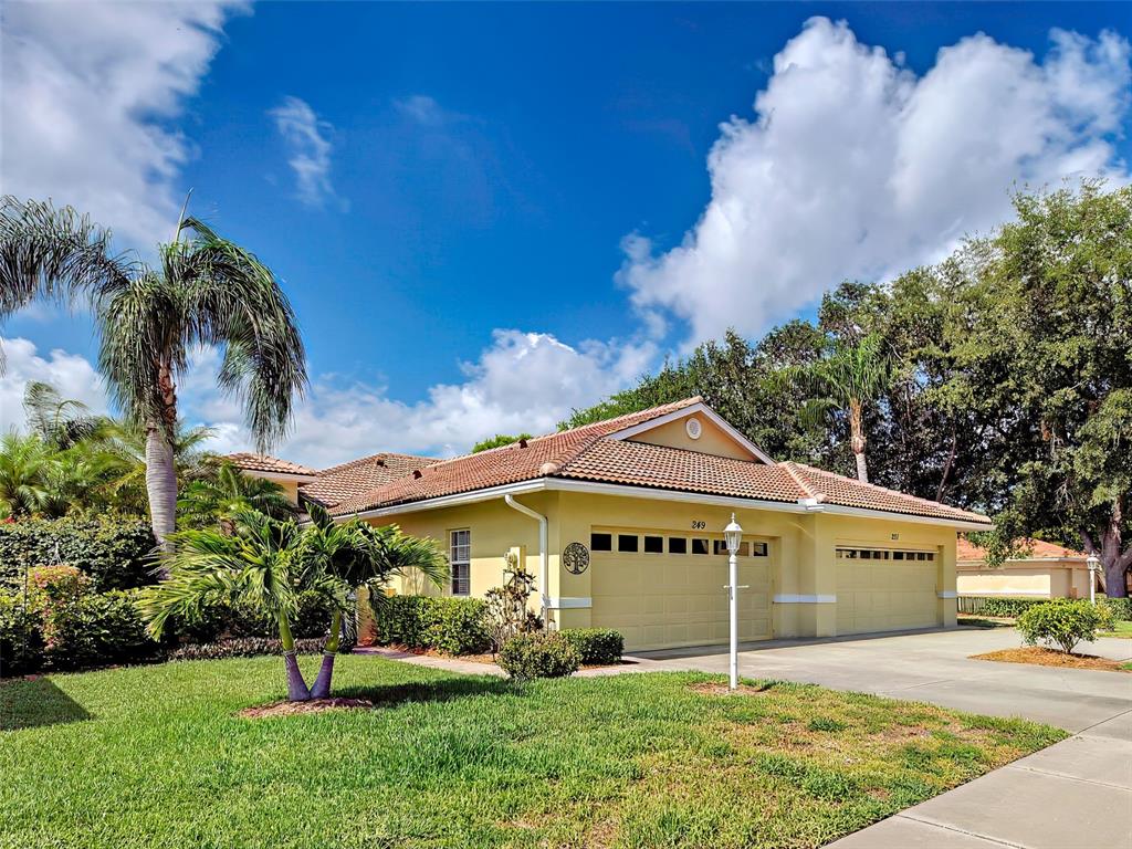 A yellow single-story house with a tile roof and a three-car garage — 249 VISTA DEL LAGO WAY, VENICE, FL