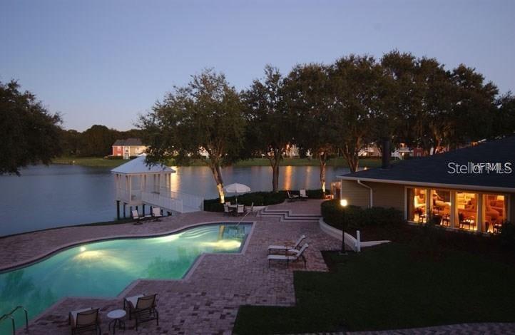 An outdoor swimming pool and patio area overlook a lake with a small gazebo — 803 LAKE HAVEN SQUARE UNIT 202, BRANDON, FL