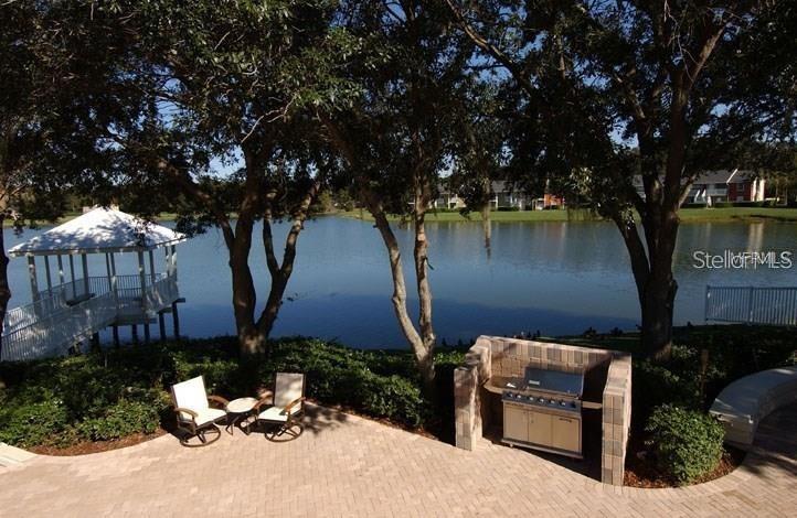A patio with a built-in grill, two chairs, and a gazebo overlooking a lake — 803 LAKE HAVEN SQUARE UNIT 202, BRANDON, FL