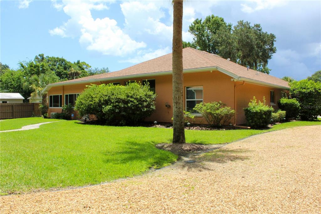 A single-story house with orange stucco walls and a gravel driveway sits on a lawn — 751 CALLE GRANDE STREET, ORMOND BEACH, FL
