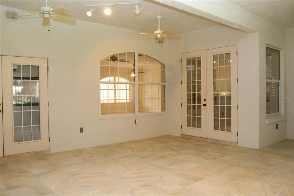 A sunroom features tile flooring, two ceiling fans, track lighting, and multiple glass-paned doors — 751 CALLE GRANDE STREET, ORMOND BEACH, FL