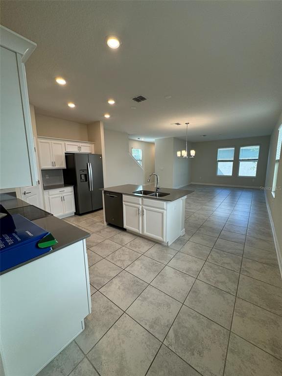 A kitchen with white cabinets, dark countertops, and tile flooring opens into a dining area — 14252 TITLE WAY, WINTER GARDEN, FL