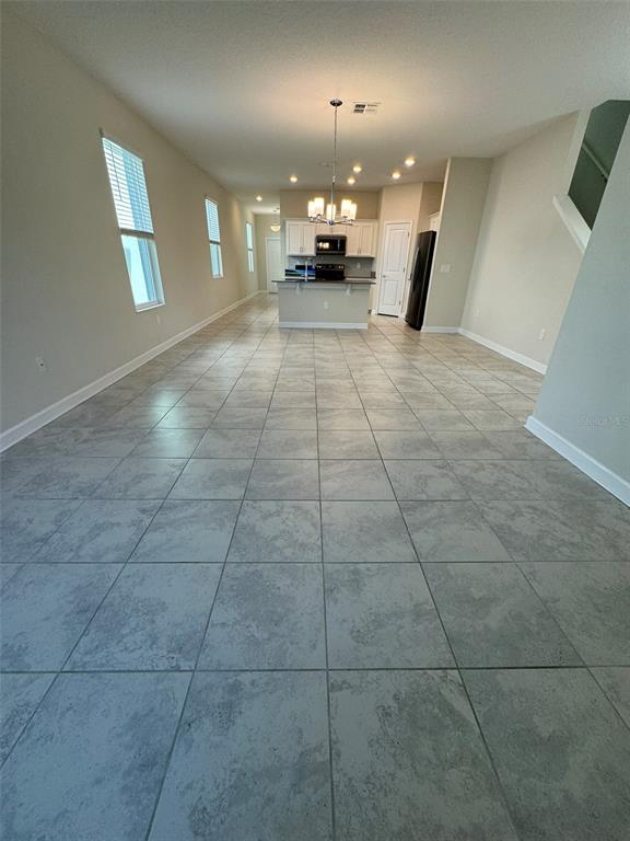 An open-concept kitchen and living area features light gray tile flooring and white cabinetry — 14252 TITLE WAY, WINTER GARDEN, FL