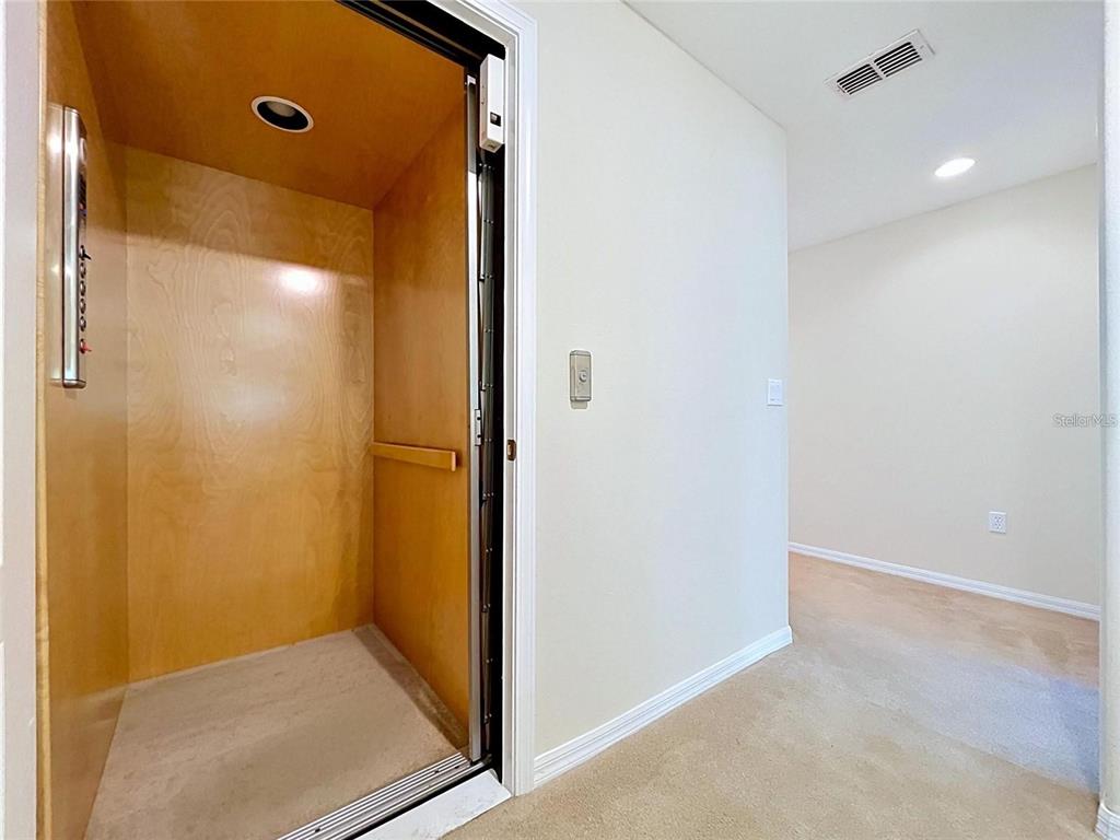 An open residential elevator with wood paneling is situated next to a carpeted hallway — 10144 ARBOR RUN DRIVE UNIT 31, TAMPA, FL