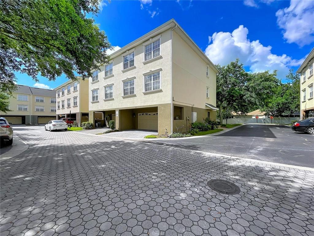 A three-story townhouse building with a ground-level garage and paved driveway under a blue sky — 10144 ARBOR RUN DRIVE UNIT 31, TAMPA, FL