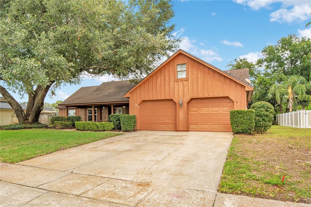 A single-story house with wood siding, a two-car garage, and a large oak tree — 5307 JADE CIRCLE, ORLANDO, FL