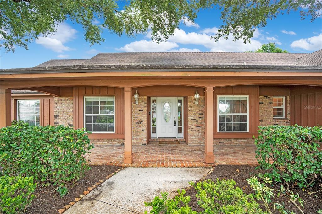The exterior of a single-story brick house features a covered porch and a front door — 5307 JADE CIRCLE, ORLANDO, FL