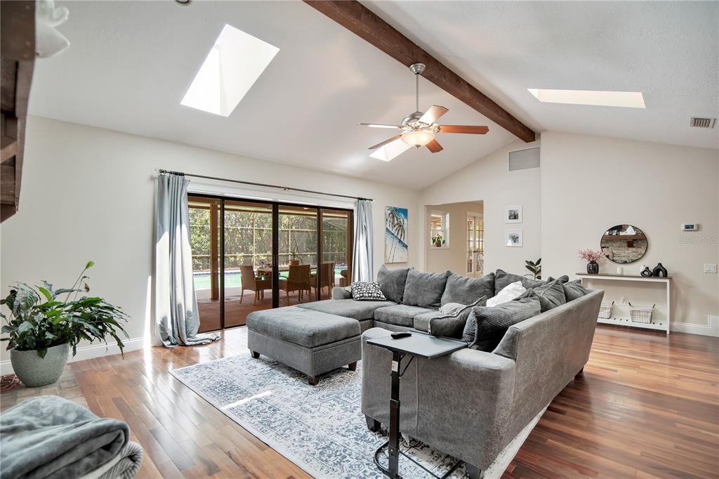A living room with hardwood floors, a sectional sofa, a ceiling fan, and skylights — 5307 JADE CIRCLE, ORLANDO, FL