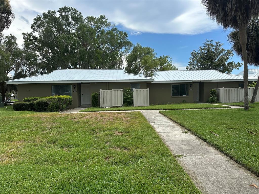 A single-story duplex with a metal roof, tan exterior, and a concrete walkway — 11261 W BAYSHORE DRIVE UNIT 82, CRYSTAL RIVER, FL