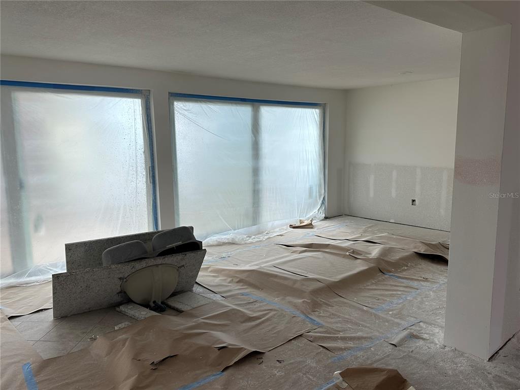An unfinished room features large windows covered in plastic, a detached vanity, and paper-covered floors — 11261 W BAYSHORE DRIVE UNIT 82, CRYSTAL RIVER, FL
