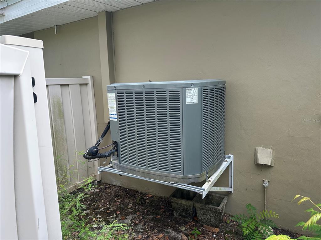 An outdoor air conditioning condenser unit is mounted on a wall bracket against a building — 11261 W BAYSHORE DRIVE UNIT 82, CRYSTAL RIVER, FL