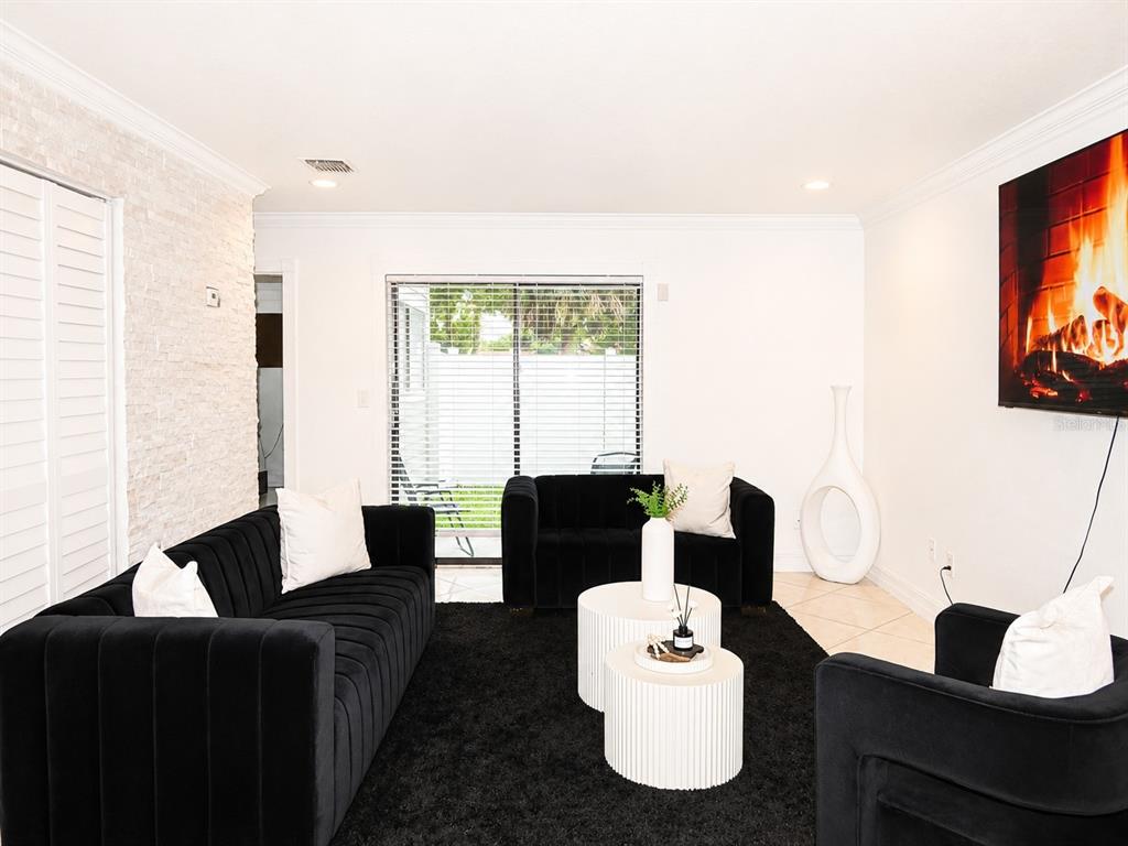 A living room features black velvet furniture, a white stone accent wall, and a fireplace television — 7298 ULMERTON ROAD UNIT 307, LARGO, FL
