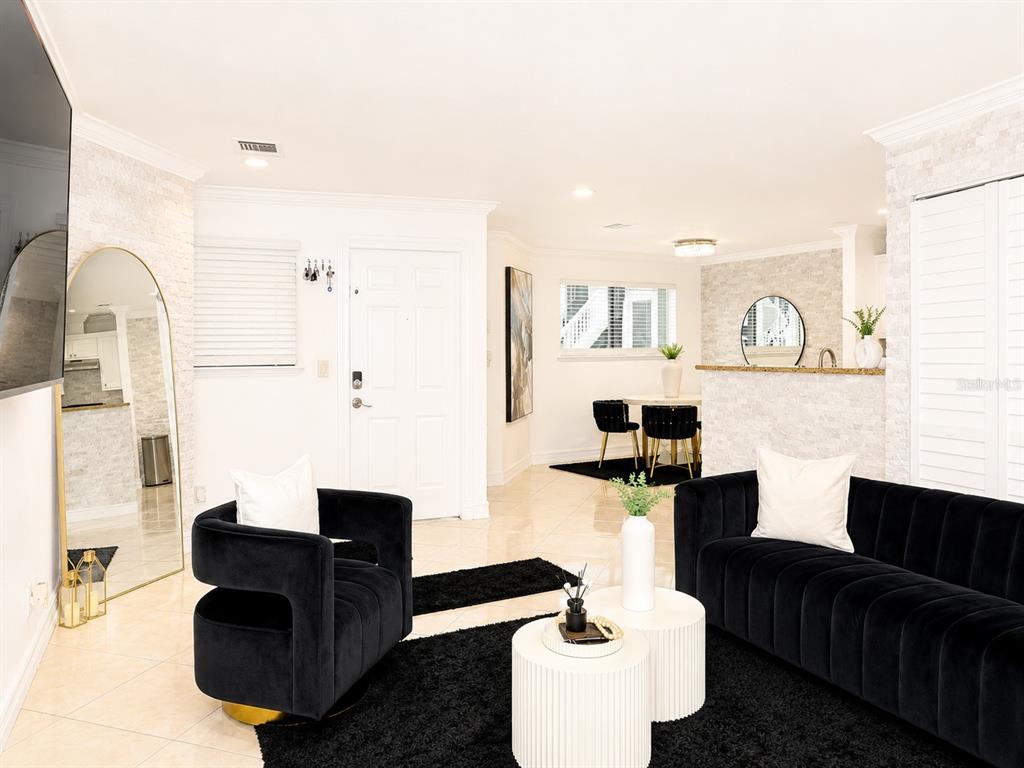 A living room features black velvet furniture, white circular tables, and light-colored stone accent walls — 7298 ULMERTON ROAD UNIT 307, LARGO, FL