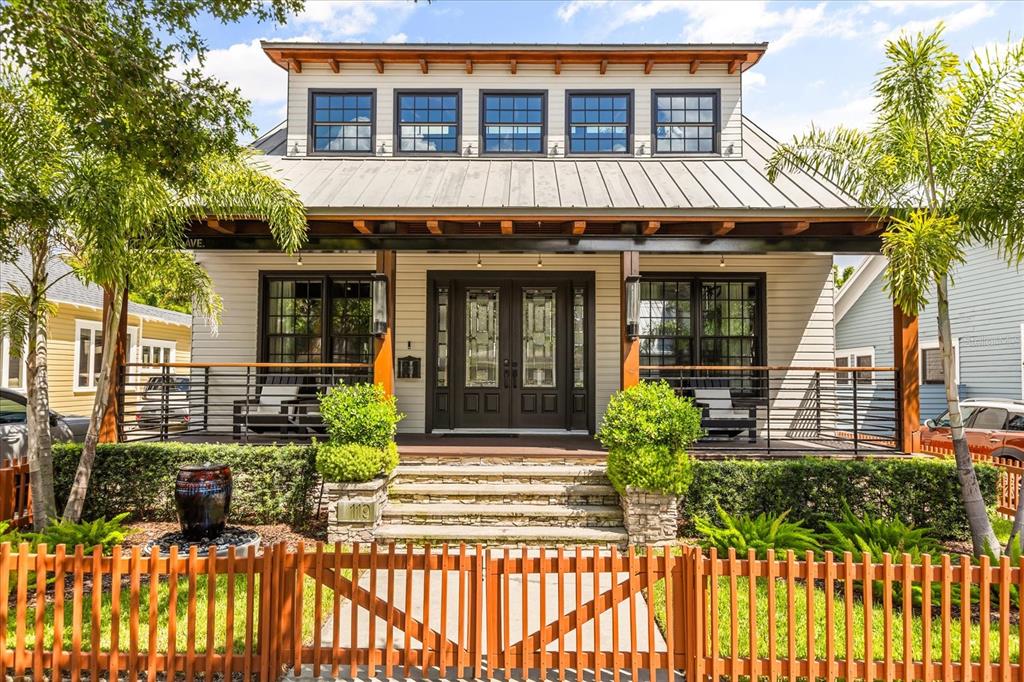 A covered wooden porch features modern black chairs, a metal railing, and exposed wood beams — 119 N HYER AVENUE, ORLANDO, FL