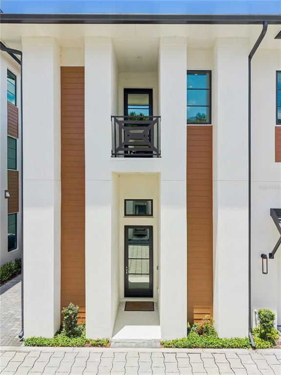 A modern townhouse exterior features white stucco walls, wood-look siding, and a black-framed front door — 512 W SWOOPE AVENUE, WINTER PARK, FL