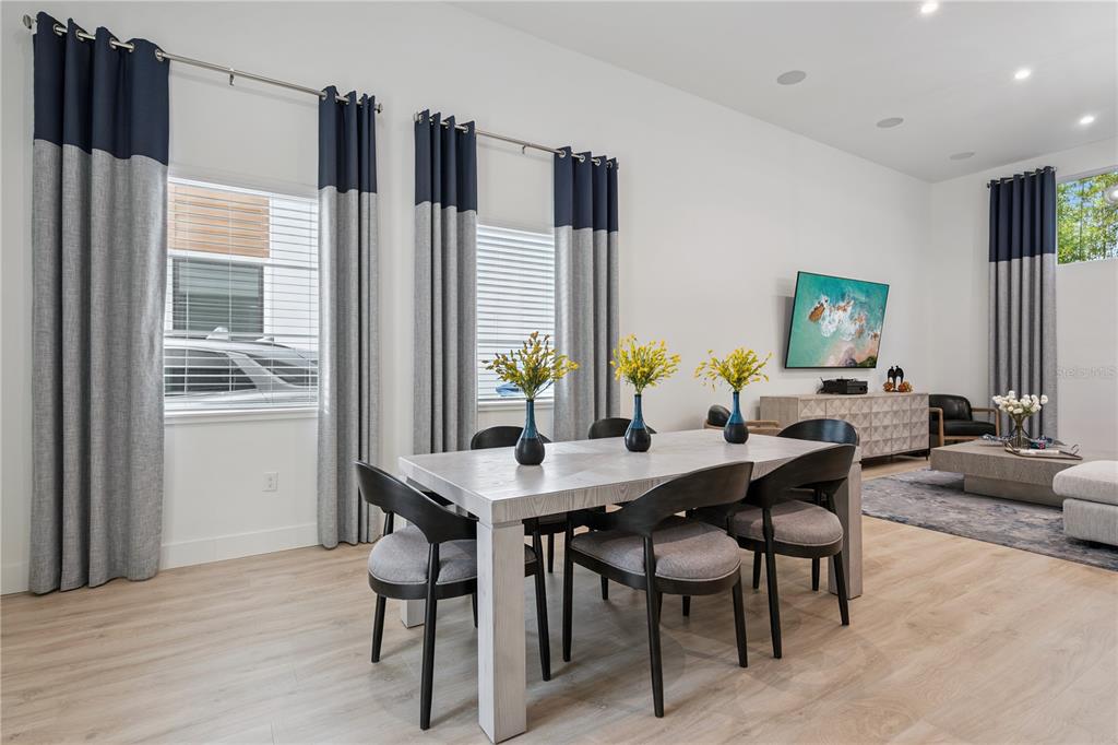 A dining area features a light wood table, dark chairs, and floor-to-ceiling two-toned curtains — 512 W SWOOPE AVENUE, WINTER PARK, FL