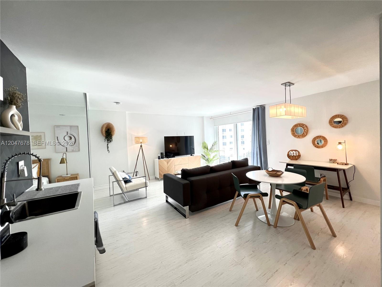 A bright, open-concept living and dining area features light wood flooring and modern furniture — 345 Ocean Dr # 525, Miami Beach FL 33139, MIAMI BEACH, FL
