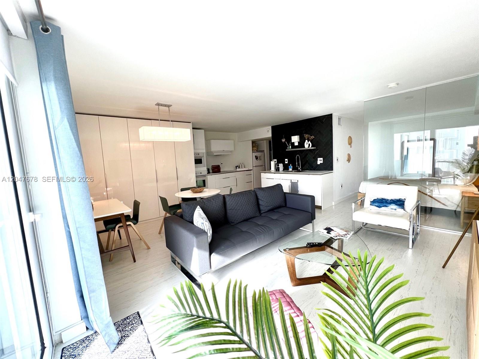A modern open-concept living area features a dark sofa, dining space, and kitchen with cabinetry — 345 Ocean Dr # 525, Miami Beach FL 33139, MIAMI BEACH, FL