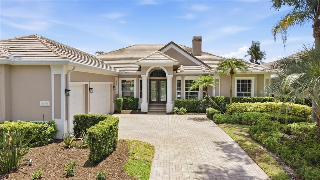 A single-story house with a beige stucco exterior, a tiled roof, and a paved driveway — 8160 COLLINGWOOD COURT, UNIVERSITY PARK, FL