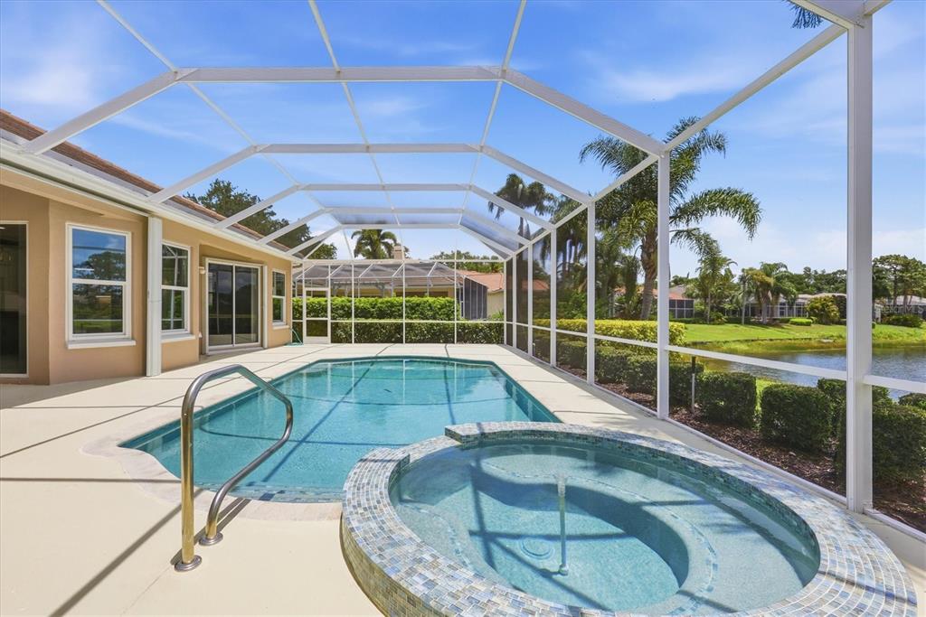 A screened-in pool and spa area with a view of a pond and palm trees — 8160 COLLINGWOOD COURT, UNIVERSITY PARK, FL