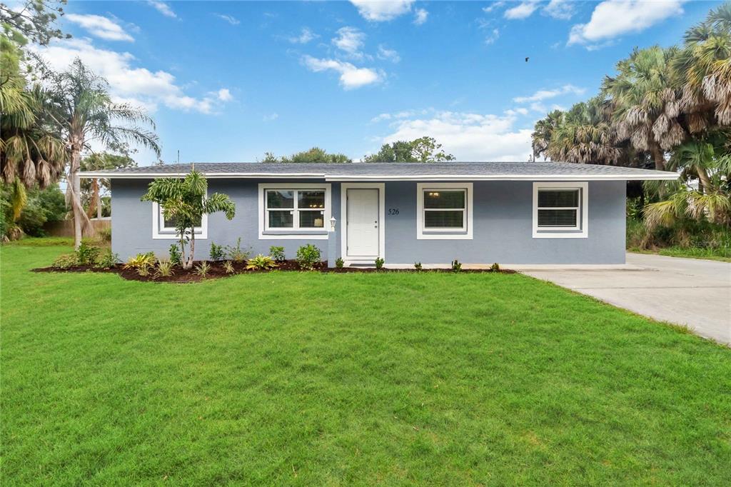A single-story house with blue painted brick, a white front door, and a grassy lawn — 526 CONRAD ROAD, VENICE, FL