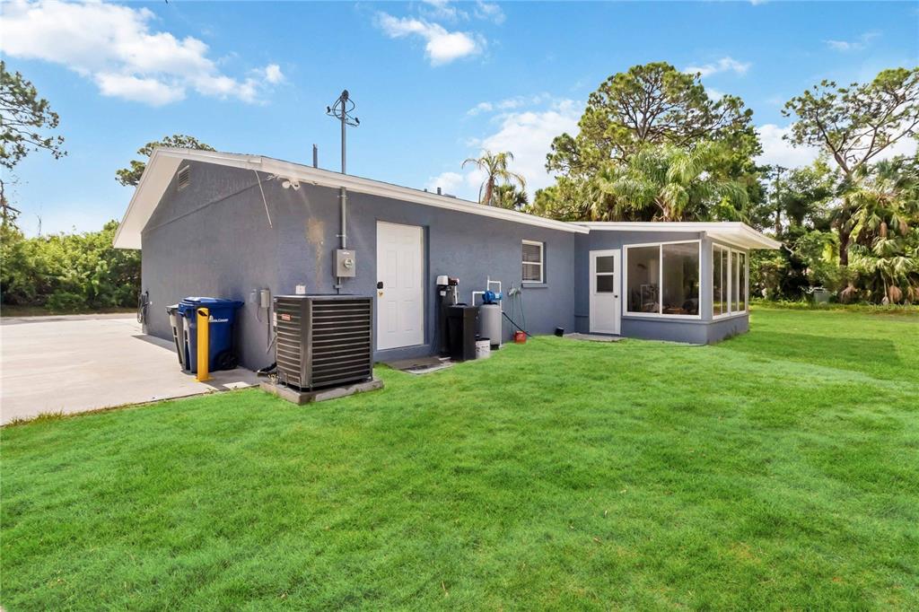 The exterior of a gray house features a concrete driveway, HVAC unit, and grassy yard — 526 CONRAD ROAD, VENICE, FL