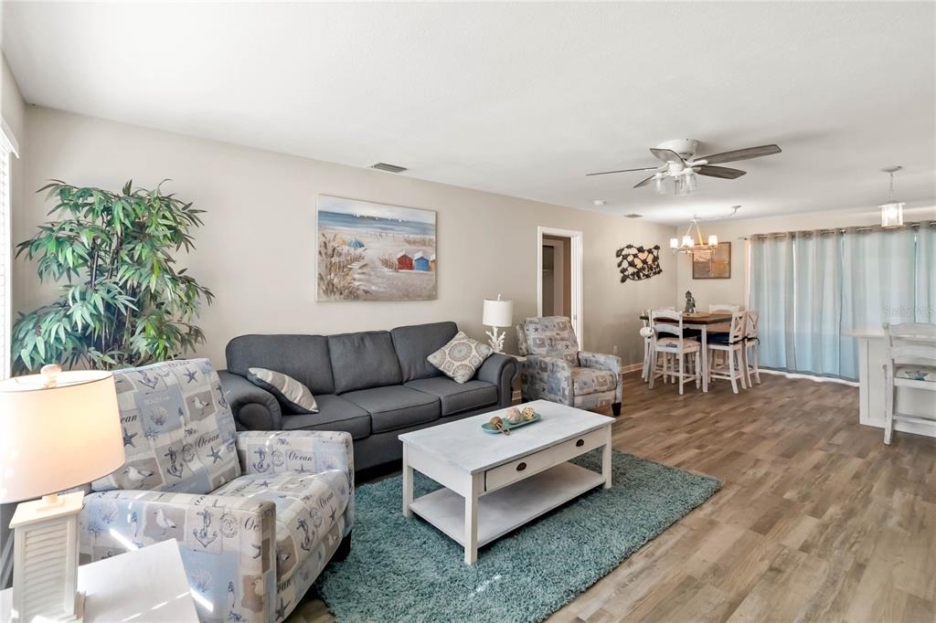 A living room features a gray sofa, patterned armchairs, a coffee table, and wood-look flooring — 526 CONRAD ROAD, VENICE, FL