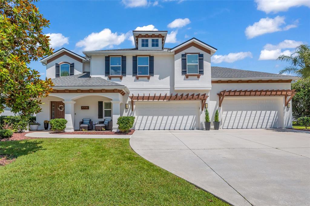 A two-story house with a white stucco exterior, a three-car garage, and a front porch — 6835 STONEHEATH LANE, PORT ORANGE, FL