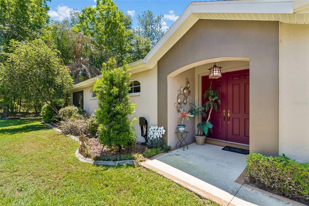 A house exterior features a red double front door under a covered entryway — 5212 ESPLANDE COURT, BROOKSVILLE, FL
