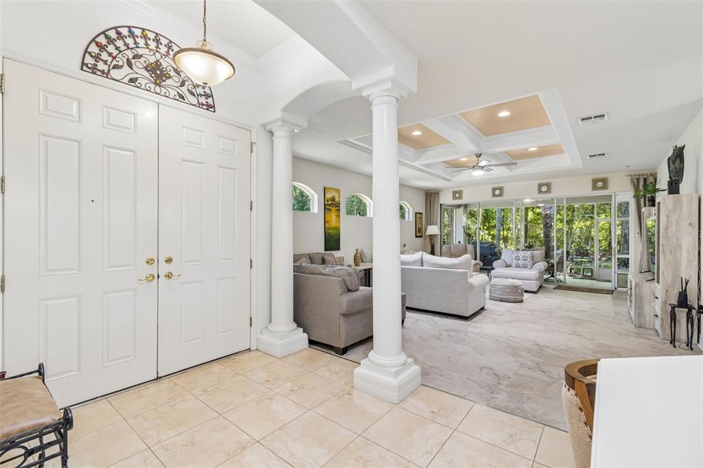 A bright entryway with white double doors leads into a spacious living room with columns — 5212 ESPLANDE COURT, BROOKSVILLE, FL