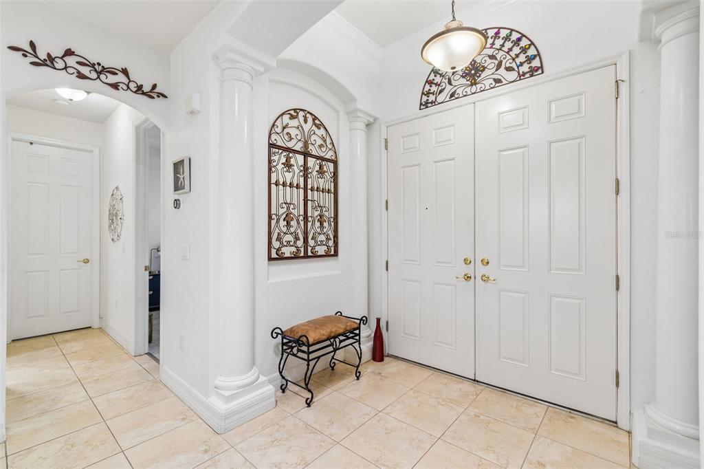 An entryway features white double doors, tiled floors, decorative wall metalwork, and a small bench — 5212 ESPLANDE COURT, BROOKSVILLE, FL