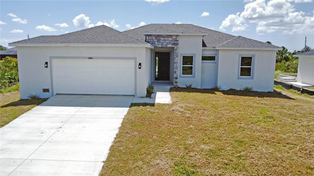 A single-story house with a white stucco exterior, stone accents, and a two-car garage — 13558 JERONIMO LANE, PORT CHARLOTTE, FL