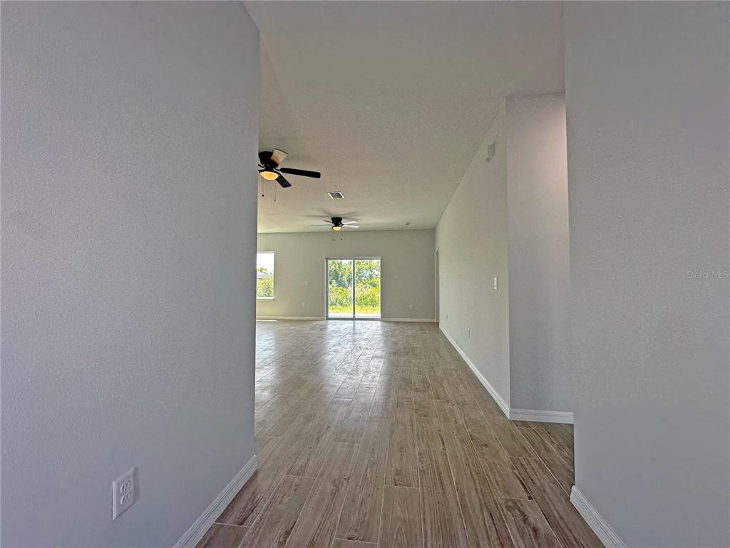 An interior view of a room with light gray walls, wood-look tile flooring, and ceiling fans — 13558 JERONIMO LANE, PORT CHARLOTTE, FL