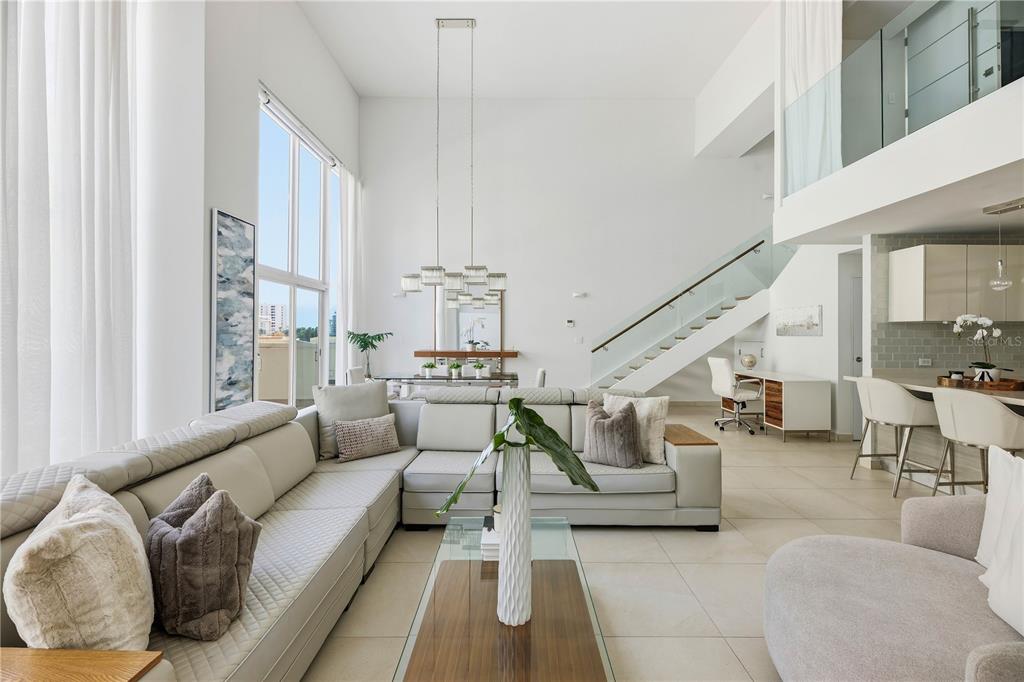 A modern, open-concept living room features high ceilings, a large sectional sofa, and a staircase — 25 MUNOZ RIVERA AVENUE UNIT 421, SAN JUAN, PR