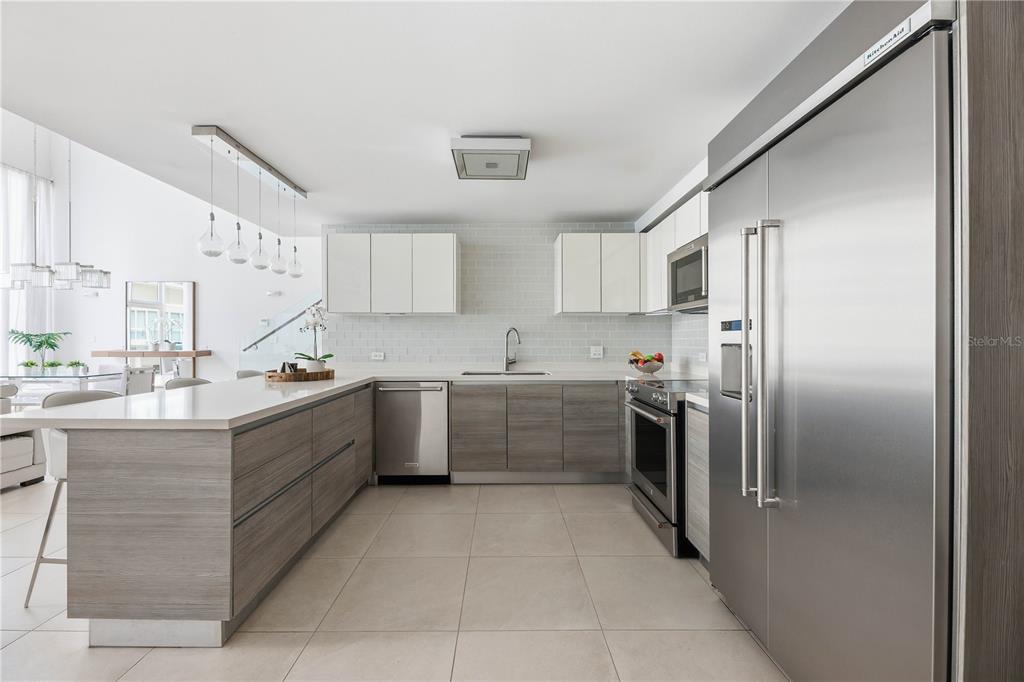 A modern kitchen features wood-grain lower cabinets, white upper cabinets, stainless steel appliances, and tile flooring — 25 MUNOZ RIVERA AVENUE UNIT 421, SAN JUAN, PR