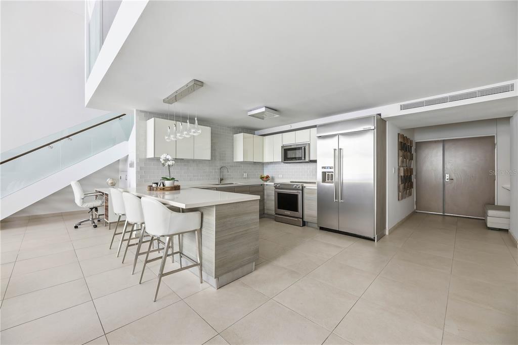 A modern kitchen features white cabinets, stainless steel appliances, a breakfast bar, and tile flooring — 25 MUNOZ RIVERA AVENUE UNIT 421, SAN JUAN, PR