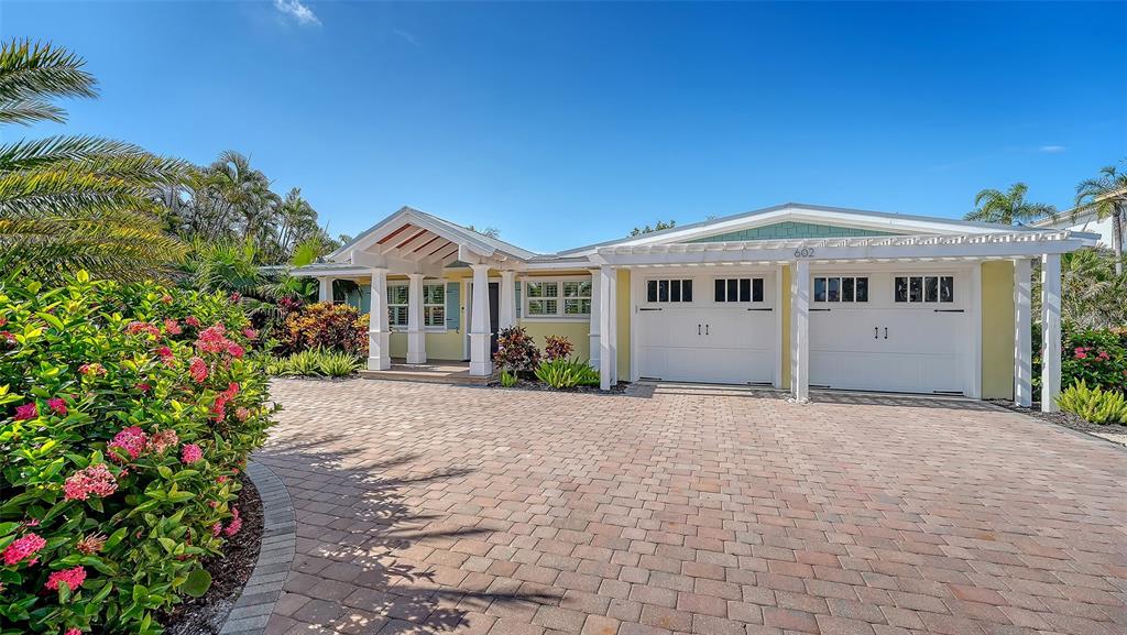 A single-story house with a paved driveway, white garage doors, and a covered entryway — 602 BUTTONWOOD DRIVE, LONGBOAT KEY, FL