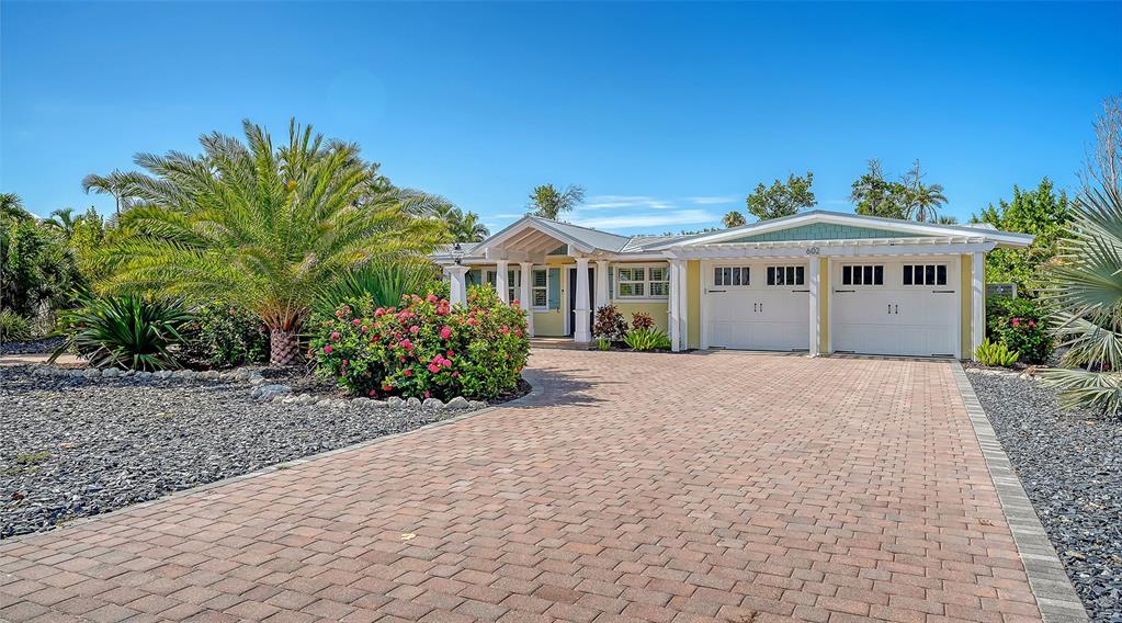 A single-story house with a paved driveway, a two-car garage, and lush tropical landscaping — 602 BUTTONWOOD DRIVE, LONGBOAT KEY, FL